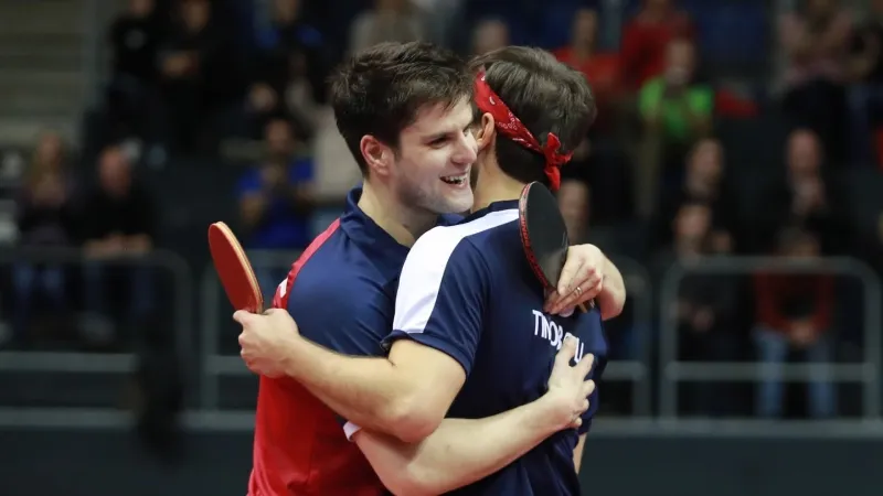 Germany's Timo Boll and Dimitrij Ovtcharov hugging on court after a Men's Team event victory
