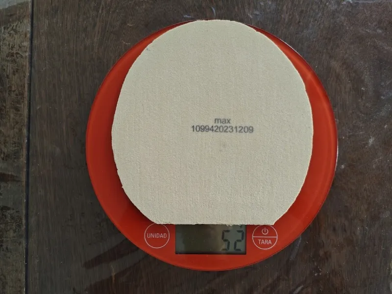 Circular rubber cut from the Victas V22 Double Extra sheet on a kitchen scale reading 52 grams