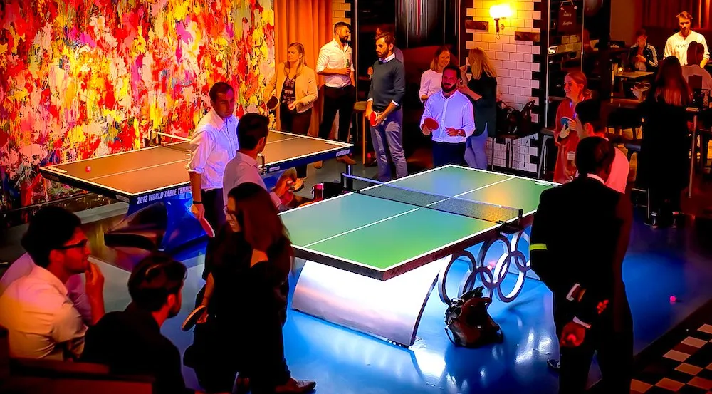 Social table tennis venue with a lit table set up in a colourful neon-lit bar lounge